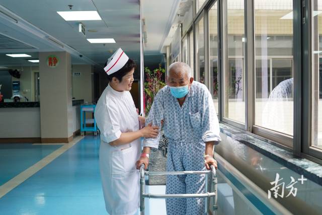在广州市第一人民医院老年医学科肾病科病房走廊，刘丽兰搀扶着患者散步。 南方+ 许舒智 拍摄